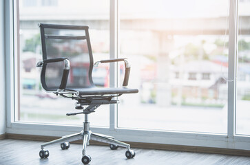 Black working chair in white office room with sunlight.