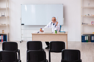 Old male doctor lecturer in the classroom during pandemic