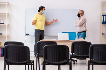 Young male student and experienced teacher in pandemic concept