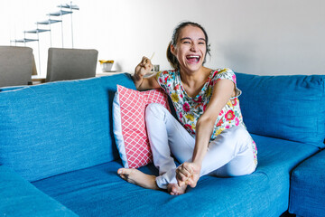 mexican disabled teen girl with cerebral palsy sitting on the couch at home in disability concept...