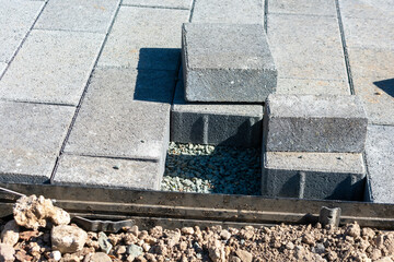 Gray stone pavers installation in progress. Cut paving stones, edge restraints, gravel base.