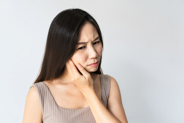 Fototapeta premium Portrait of woman feeling tooth pain. Closeup of sad girl suffering from teeth pain. Asian female feeling painful toothache on white background. Dental health and care, teeth problem. Copy space