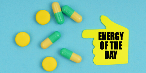 On a blue background, there are pills and a hand-sticker with the inscription - Energy of the day
