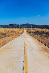 Hot temperature in straight Countryside road with dried meadow grass in two sides with clear blue sky for travel concept idea