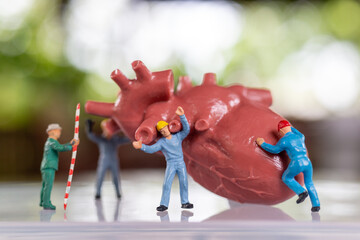 Miniature people Worker team examines the heart listen to a heartbeat and make a...