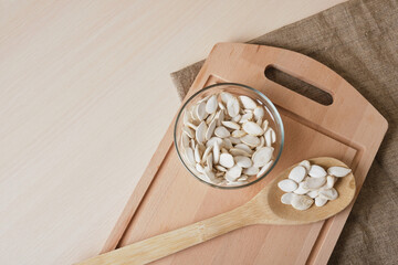 Pumpkin seeds in white bowl and spoon on the flax on the table