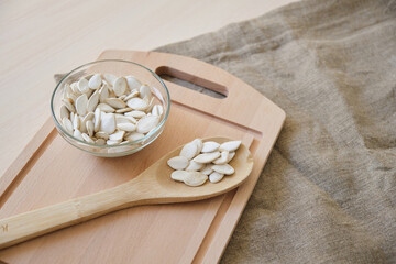 Pumpkin seeds in white bowl and spoon on the flax on the table