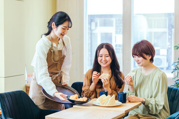 カフェ・飲食店にきた女性たちとホールスタッフ
