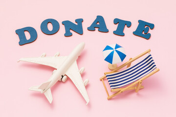 Donate word, toy plane, beach umbrella and deck chair on pink background, concept on vacation donation theme