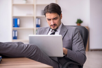 Young attractive male employee sitting at workplace