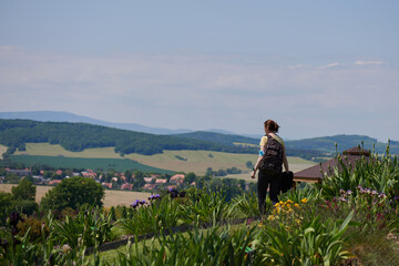 Girl exploring a garden, park, nature reserve, national park in the mountains,. Colorful flowers in the foreground, country cottages are visible in the distance.