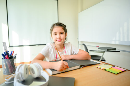 girl student elementary school looking at camera smiling happy Studying online with a tutor for education There are students studying in the classroom alone. Concept : Enjoy learning.
