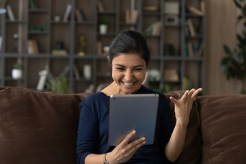 Fototapeta premium It is amazing. Emotional young lady of indian ethnicity splash hand wow look on digital tablet screen excited with great sales proposition. Euphoric teen female student get email with good exam result