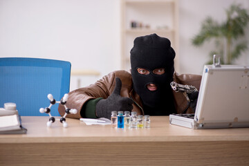 Young man in balaclava stealing vaccine from the lab