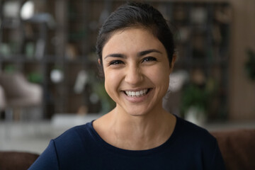 Headshot portrait of happy millennial woman of indian ethnicity make video call from home talk on...