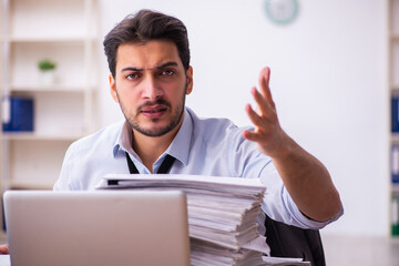 Young businessman employee unhappy with excessive work in the office