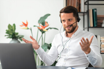Friendly caucasian man, office worker or consultant support services, uses a headset and laptop for...