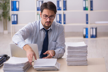 Obraz premium Young businessman employee unhappy with excessive work in the of