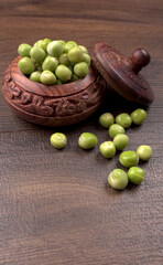 Fresh green peas in wooden bowl on wooden background.