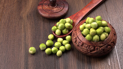 Fresh green peas in wooden bowl on wooden background.