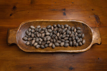 Raw in shell whole Pecan nuts in a wooden bowl on a wood table