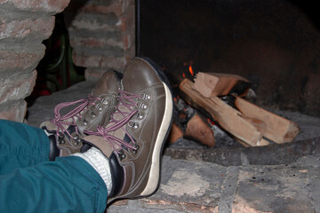 Feet warming by the fireplace in a log cabin