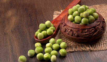 Fresh green peas in wooden bowl on wooden background.