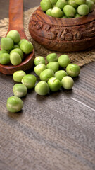 Fresh green peas in wooden bowl on wooden background.