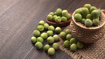 Fresh green peas in wooden bowl on wooden background.