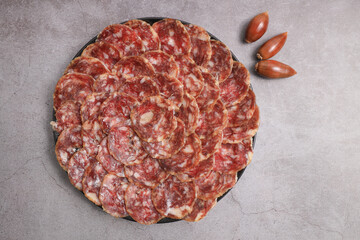 Portion of acorn-fed Iberian sausage 100% acorn on black plate decorated with acorns and gray background
