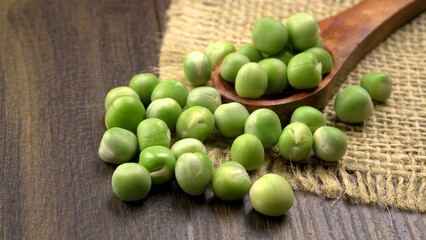 Fresh green peas in wooden bowl on wooden background.