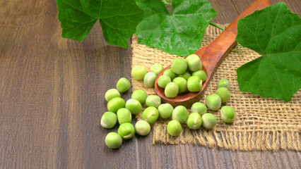 Fresh green peas in spoon on wooden background.