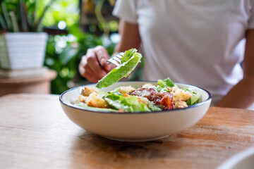 Closeup image of a woman eating a Caesar salad