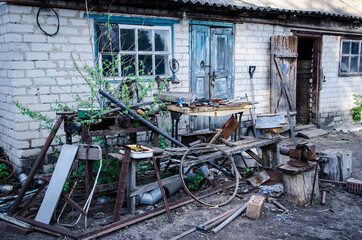 old barn in the village and a lot of iron debris near it, scrap metal, photo in the Gothic style