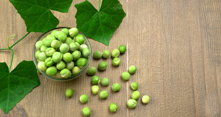 Fresh green peas in bowl on wooden background.