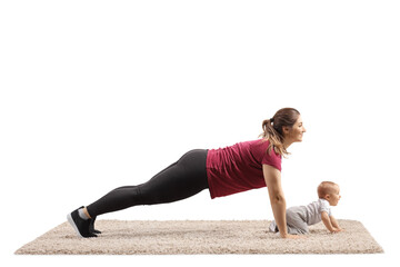 Young mother doing plank exercises with her baby crawling on carpet