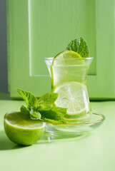 tea with mint and lime, with a calming effect, green still life close-up on a green background, top view. mojito, health drink, alternative medicine