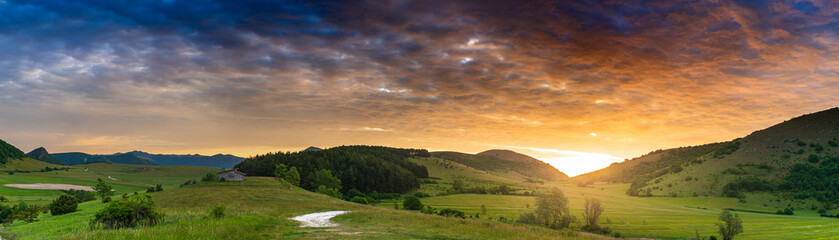 Sunset dramatic sky over Montelago highlands, Marche, Italy. Sunbeams among clouds above unique hills and mountains landscape, emotional feeling concept.