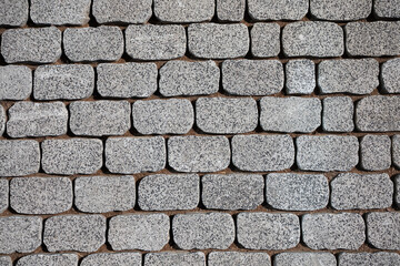Granite pavement texture. Beautiful masonry with uneven granite blocks. Stone decoration of sidewalks and pedestrian walkways. Ground texture. Perfect for background and design.