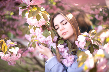 The girl lies on sakura flowers. A beautiful girl sleeps in a flower garden. Princess in the garden
