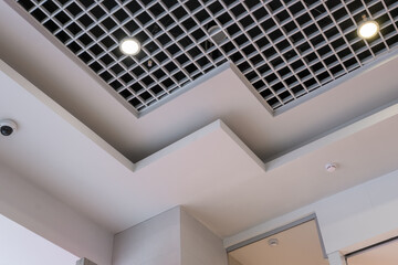 suspended and grid ceiling with halogen spots lamps and drywall construction in empty room in store or house. Stretch ceiling white and complex shape.