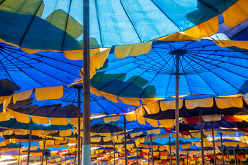 Lots of beach umbrellas of various colors that are beautifully arranged.