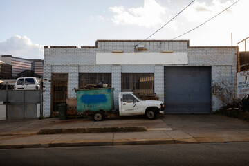 Old vehicle utility tray with custom metal scrap bin outside workshop.