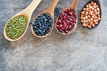 Four kinds of natural cereal and grain seeds consisted of black and red bean, mung, and peanut in wooden spoon on grunge background