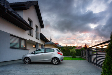 A modern single family house with a car parked outside at sunset