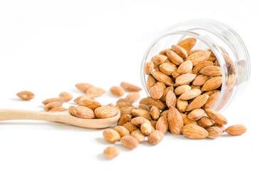 Dry organic almond seed in glass bowl with wooden spoon on white background