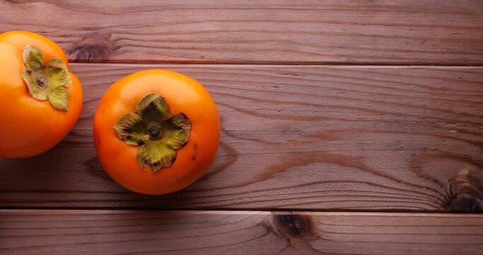 Video of a persimmon placed on a wooden board and slowly moved.