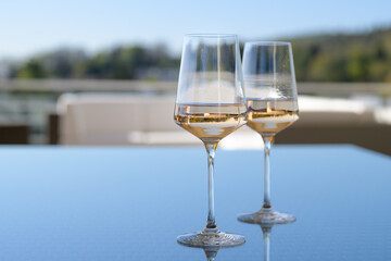 Two glasses of wine standing on an outdoor patio table