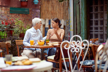 senior caucasian woman looking young adult female with smile who is explaining something to her