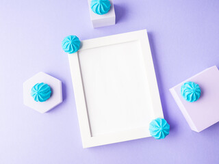 White empty frame on purple background with blue sweet decor, festive flat lay